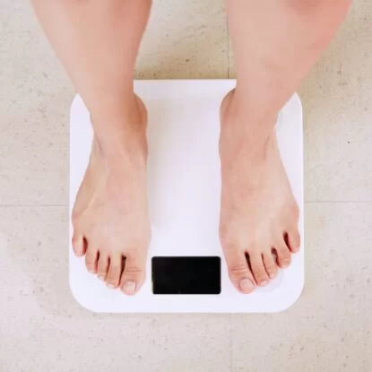 Person standing on a digital scale—symbolizing potential NMN weight loss benefits through boosted metabolism and improved cellular energy.