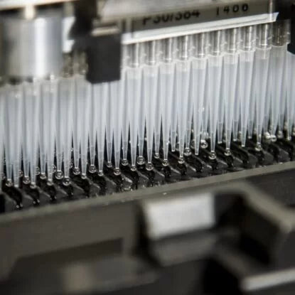 Close-up of automated pipette tips used in high-throughput DNA or genetic testing, illustrating modern genomic analysis and precision diagnostics in laboratory settings.