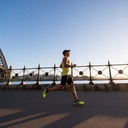 Man jogging along a waterfront during sunrise, representing the link between regular exercise and longer telomere length for healthy aging.