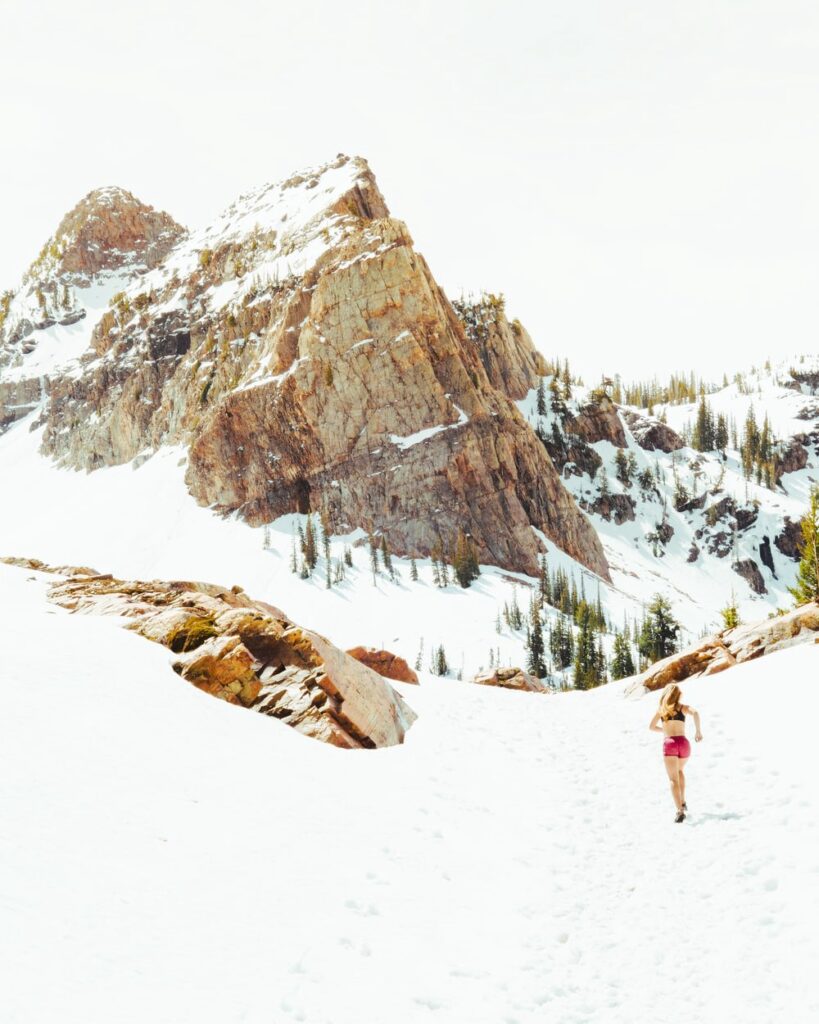 A girl in pink shorts running in the snowy mountains. Healthy lifestyle.
